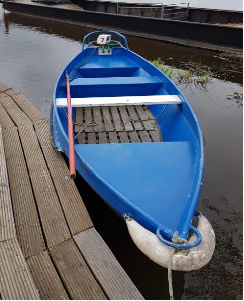 Klein blauw bootje aangemeerd bij een stijger